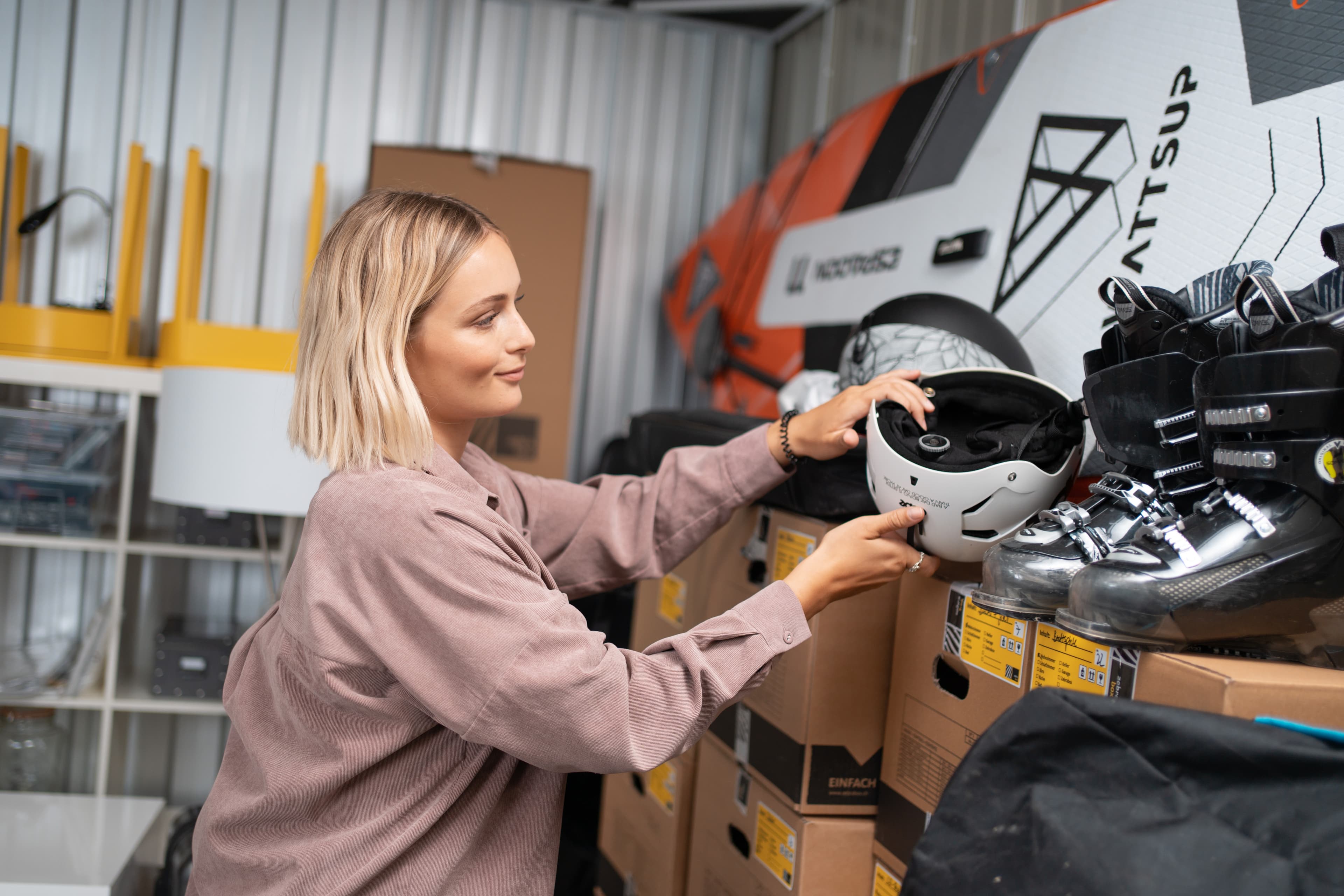 Une jeune femme range un casque de ski dans l'espace de stockage de Zebrabox.