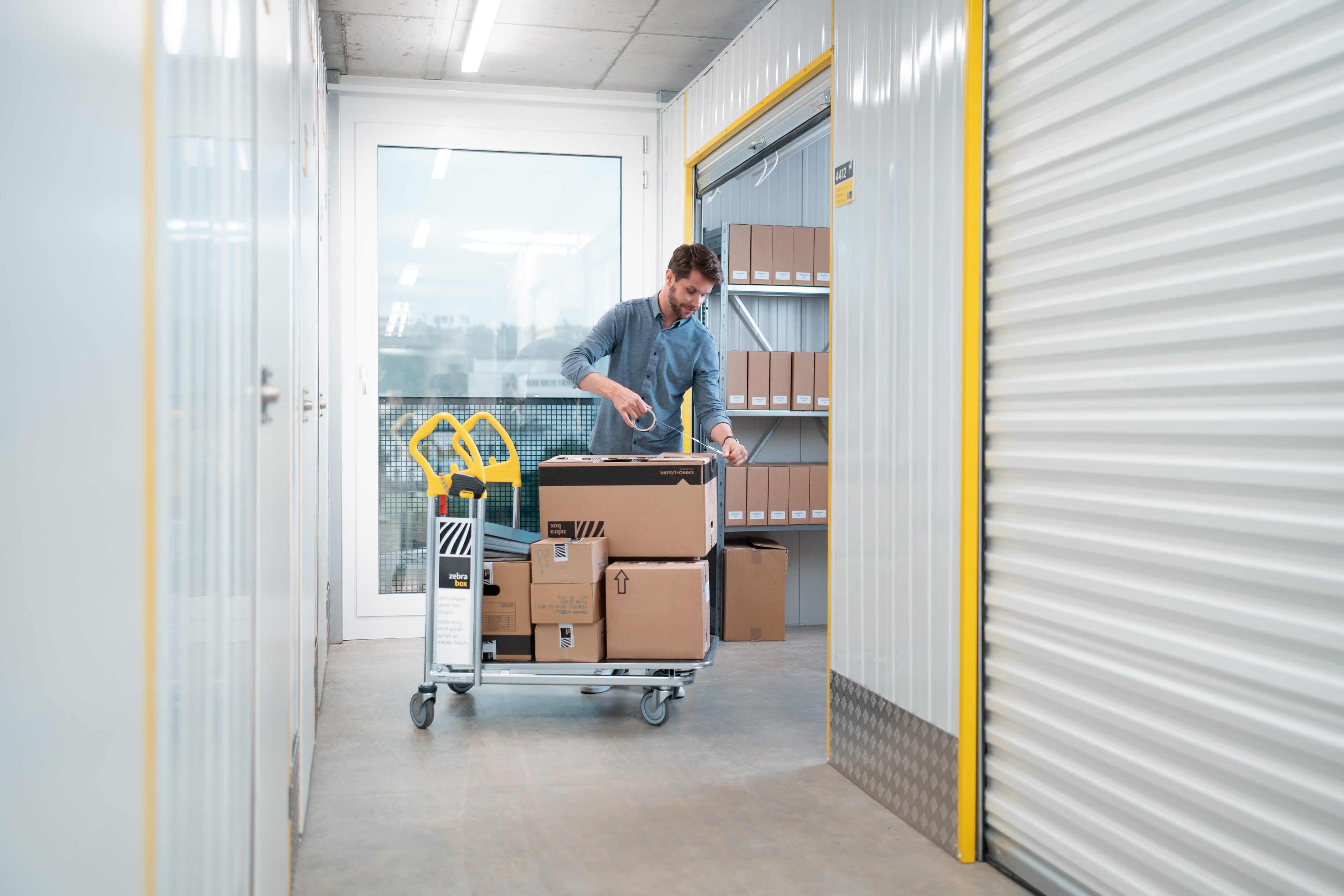 A man is storing moving boxes and archive boxes in the company warehouse at Zebrabox.