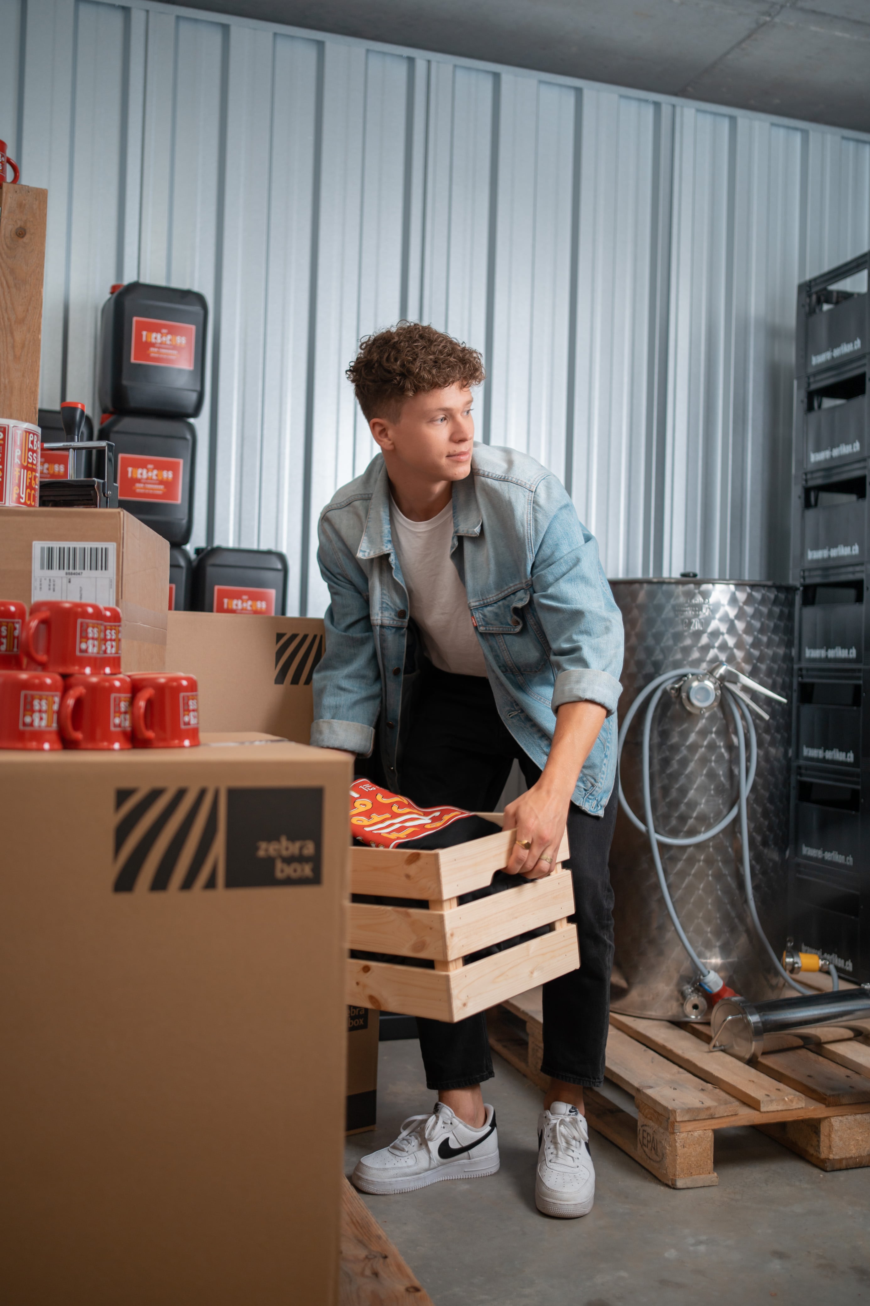A man is carrying a wooden box and placing it in the Zebrabox storage unit.