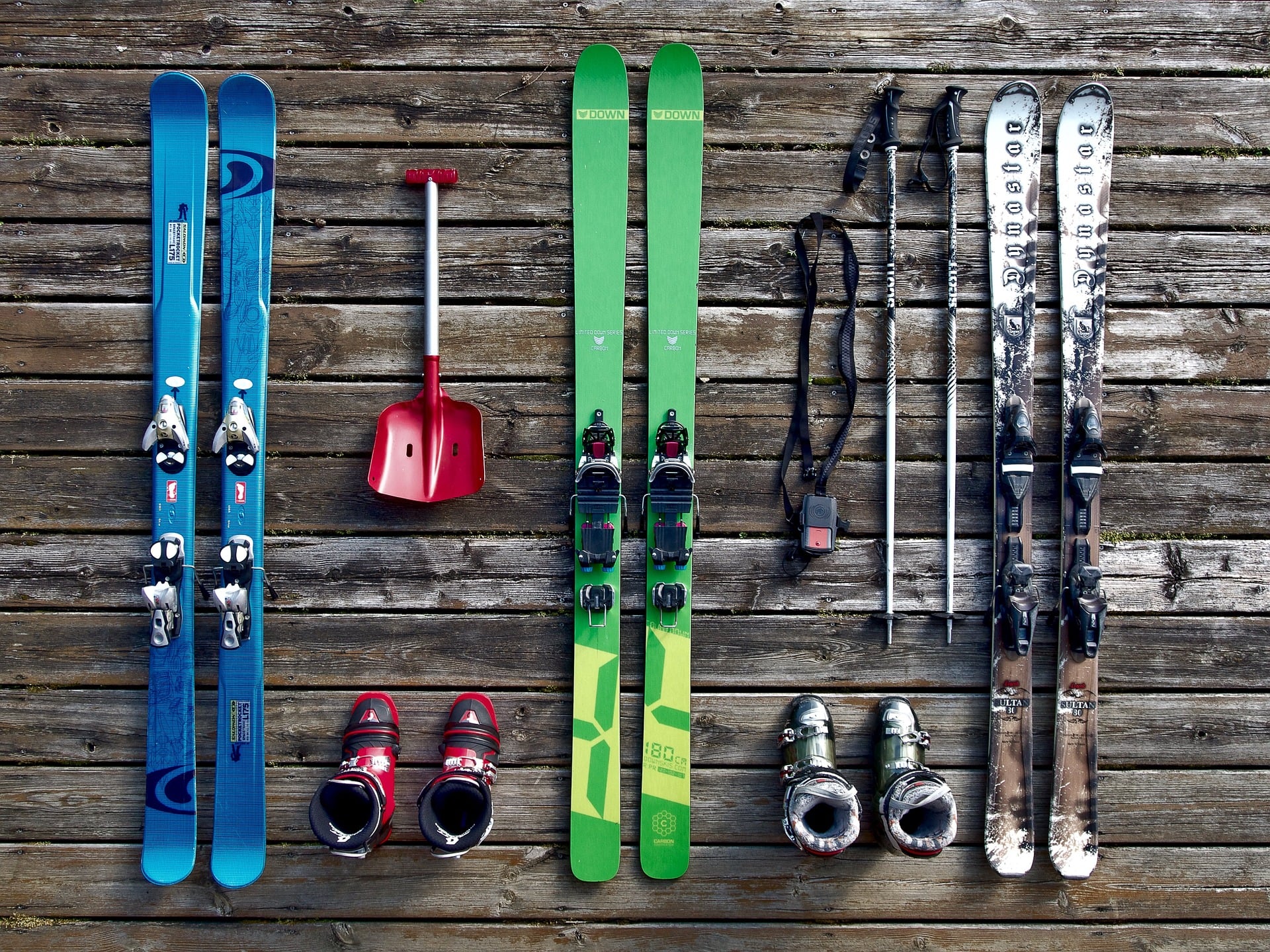 La vue aérienne permet de distinguer trois paires de skis avec des chaussures de ski, des bâtons de ski et un équipement de sauvetage en cas d'avalanche.